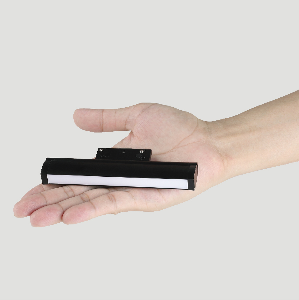 Compact magnetic track light fixture held in palm showing small size
